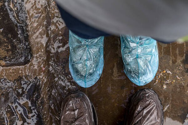 farmers wearing disposable boot covers in rainy mud